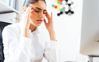 Tired businesswoman having a headache while sitting at the office desk