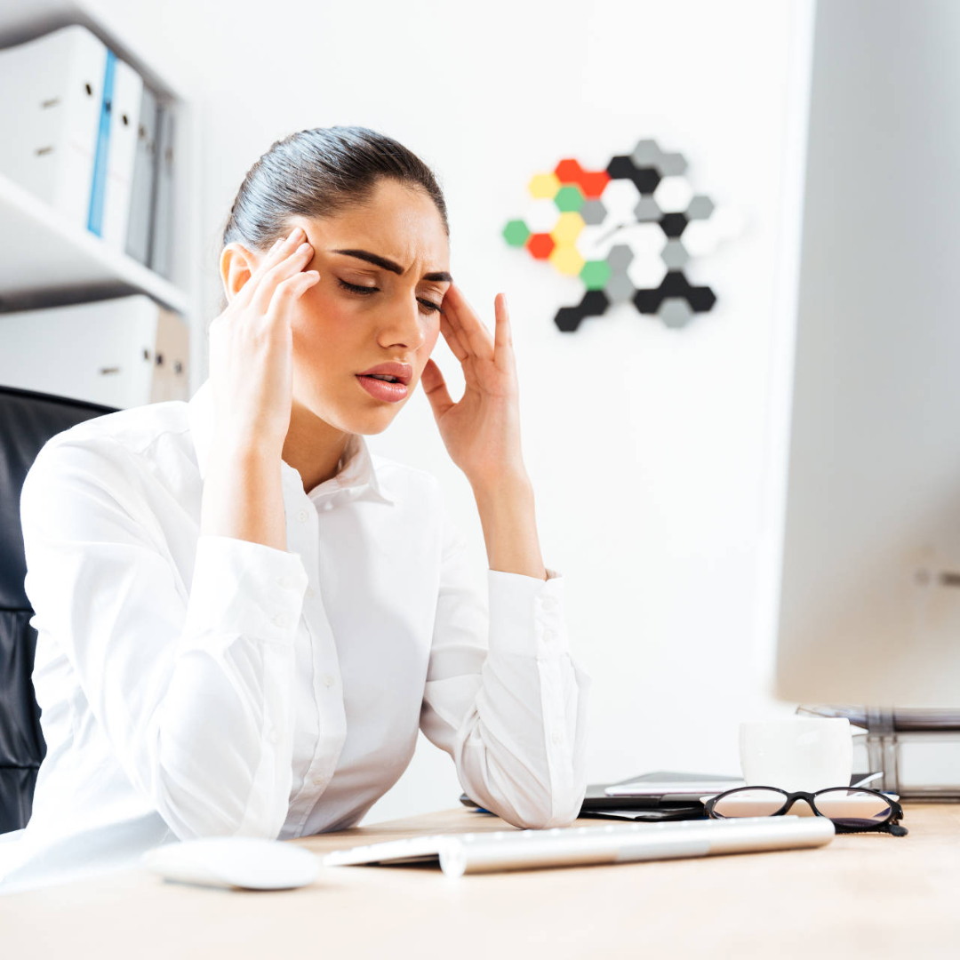 Tired businesswoman having a headache while sitting at the office desk