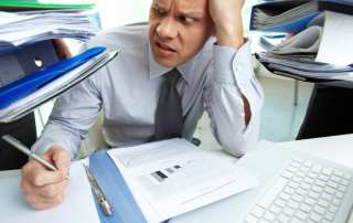 Perplexed QA-Manager looking at huge piles of documents